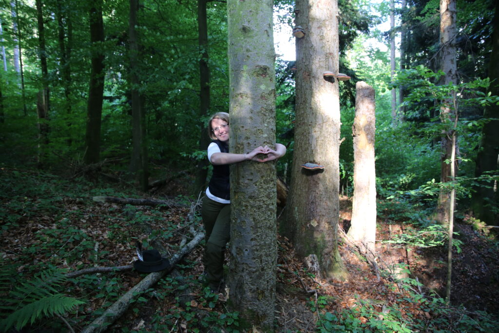 Kathi im Wald in Verbindung mit der Natur, umgeben von Bäumen als Symbol für Erdung und Harmonie